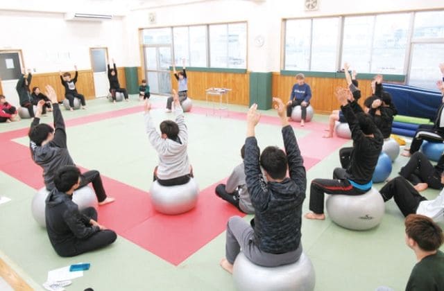 バランスボールを使って患部の機能回復・運動療法を学ぶ、柔道整復後療法演習の授業風景