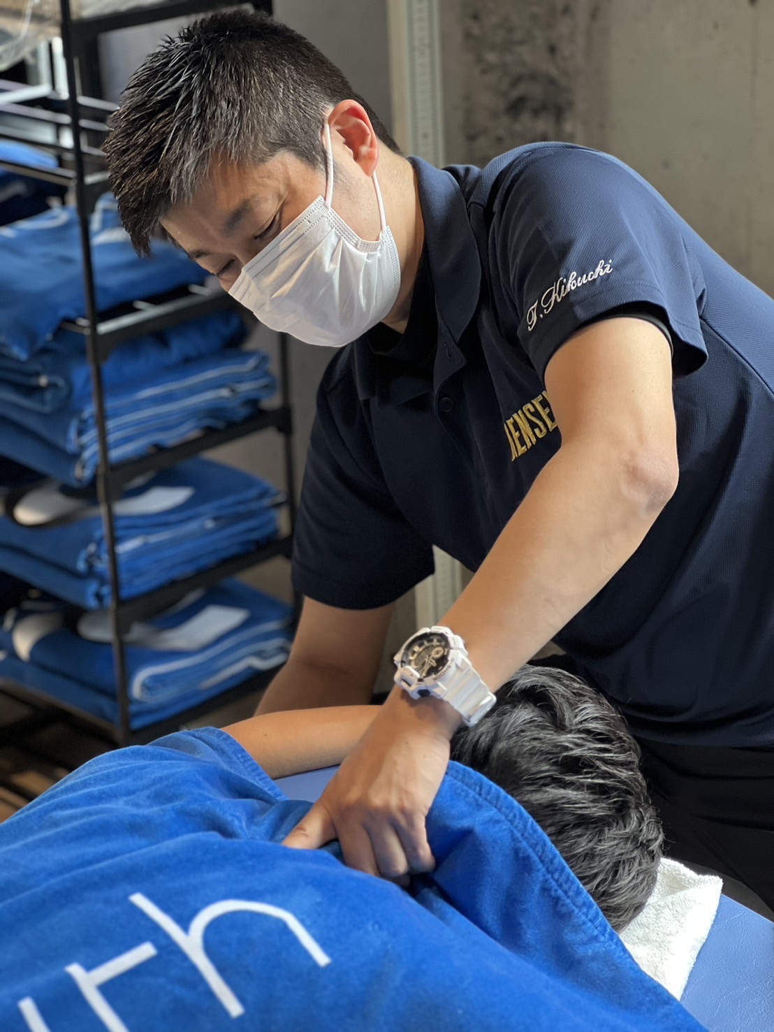 スポーツトレーナーが利用者の肩を揉みほぐしている写真です。