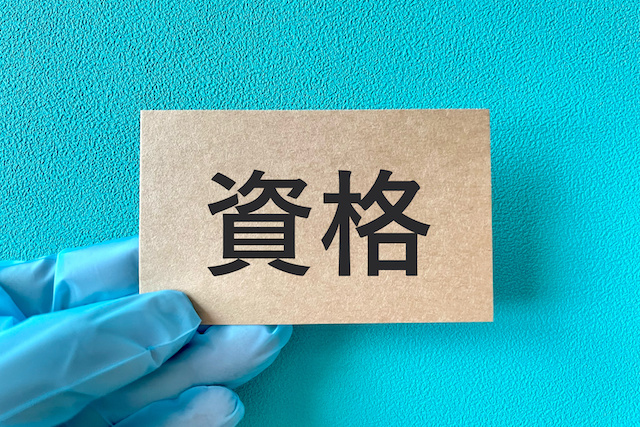 「資格」と書かれた茶色のカードを持っている写真です。