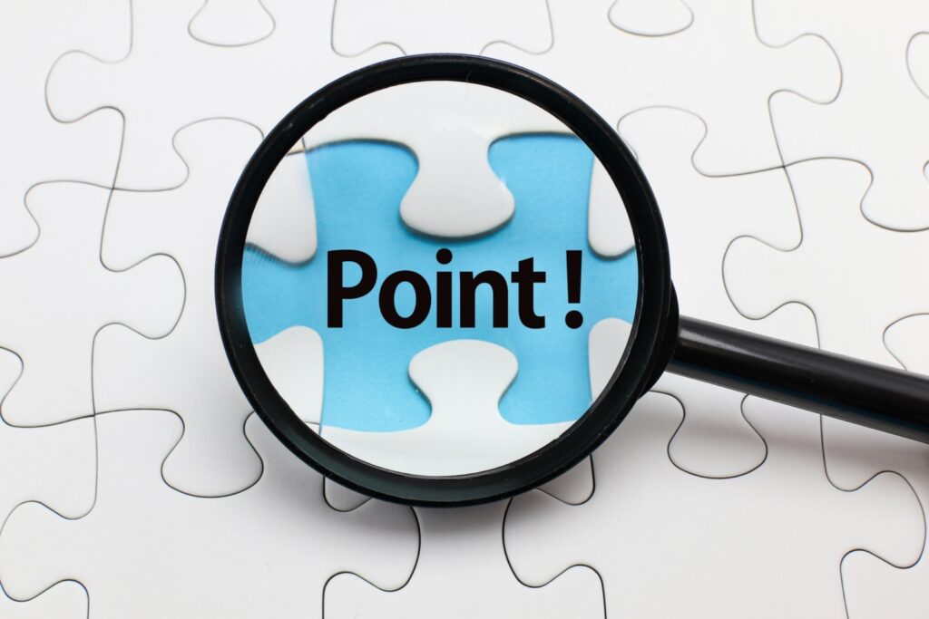 ジグソーパズルの抜けた部分にある「Point!」の文字を虫眼鏡で拡大している写真です。