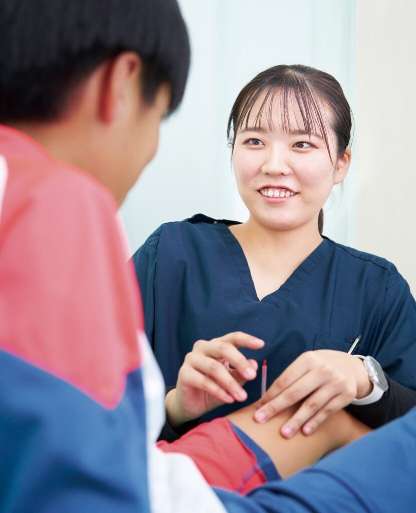 鍼灸師の女性が男性の脚に施術をしている様子の写真です。