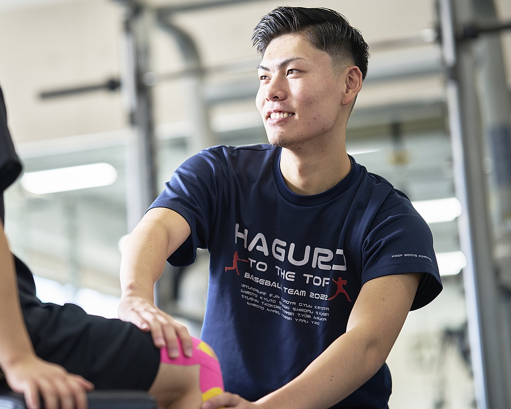 利用者の膝を確認するスポーツトレーナーの男性の写真です。